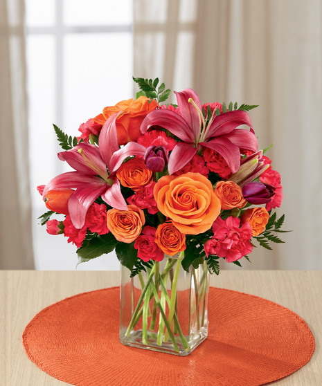 hot pink and orange floral arrangement in glass vase