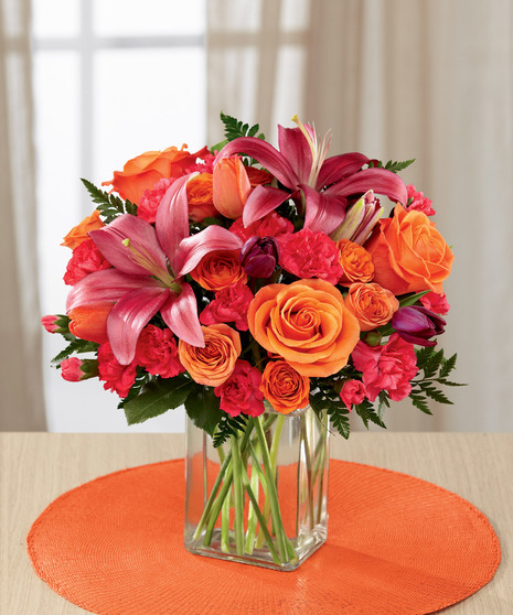 hot pink and orange floral arrangement in glass vase