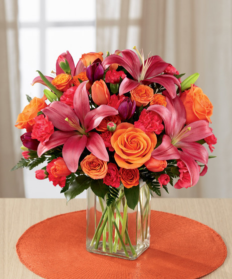 hot pink and orange floral arrangement in glass vase