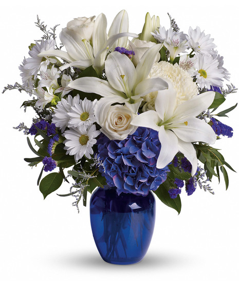 blue hydrangeas and white flowers including daisies and lilies in blue vase