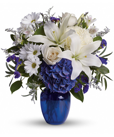 blue hydrangeas and white flowers including daisies and lilies in blue vase